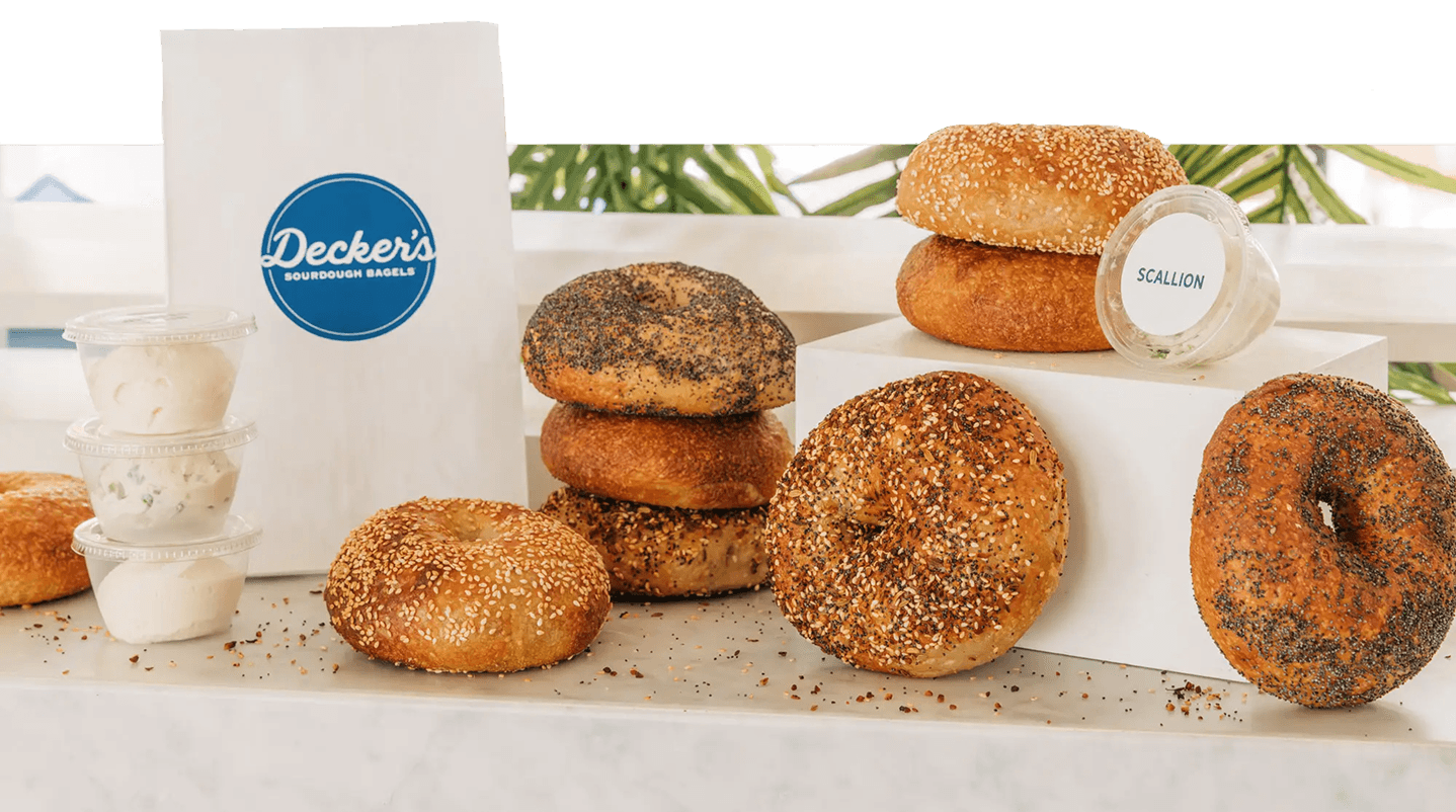 A variety of bagels and cream cheese options with a Decker's to-go bag spread on a counter